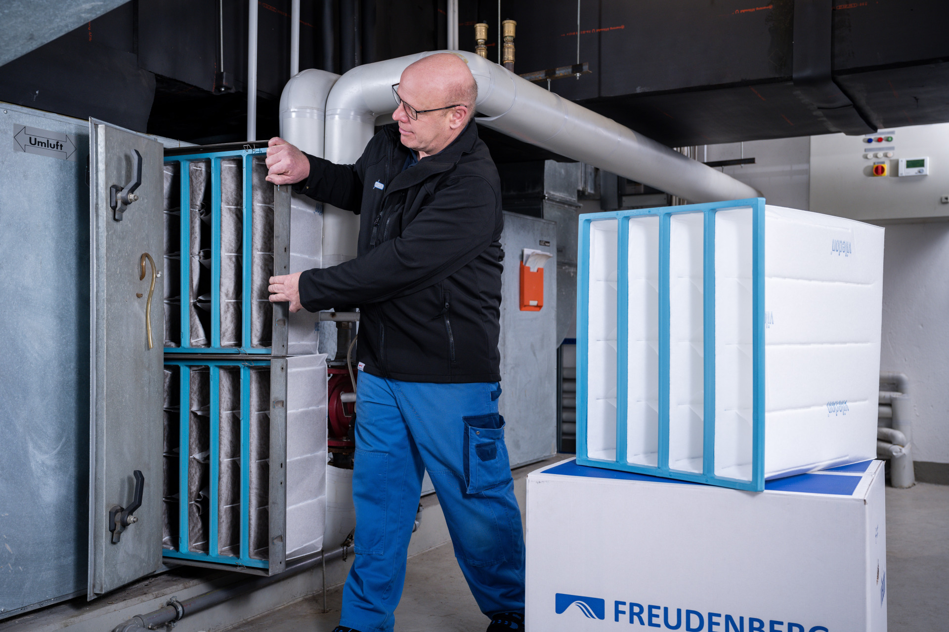Mitarbeiter von Franz Gottwald tauscht einen Luftfilter in einer industriellen Anlage.