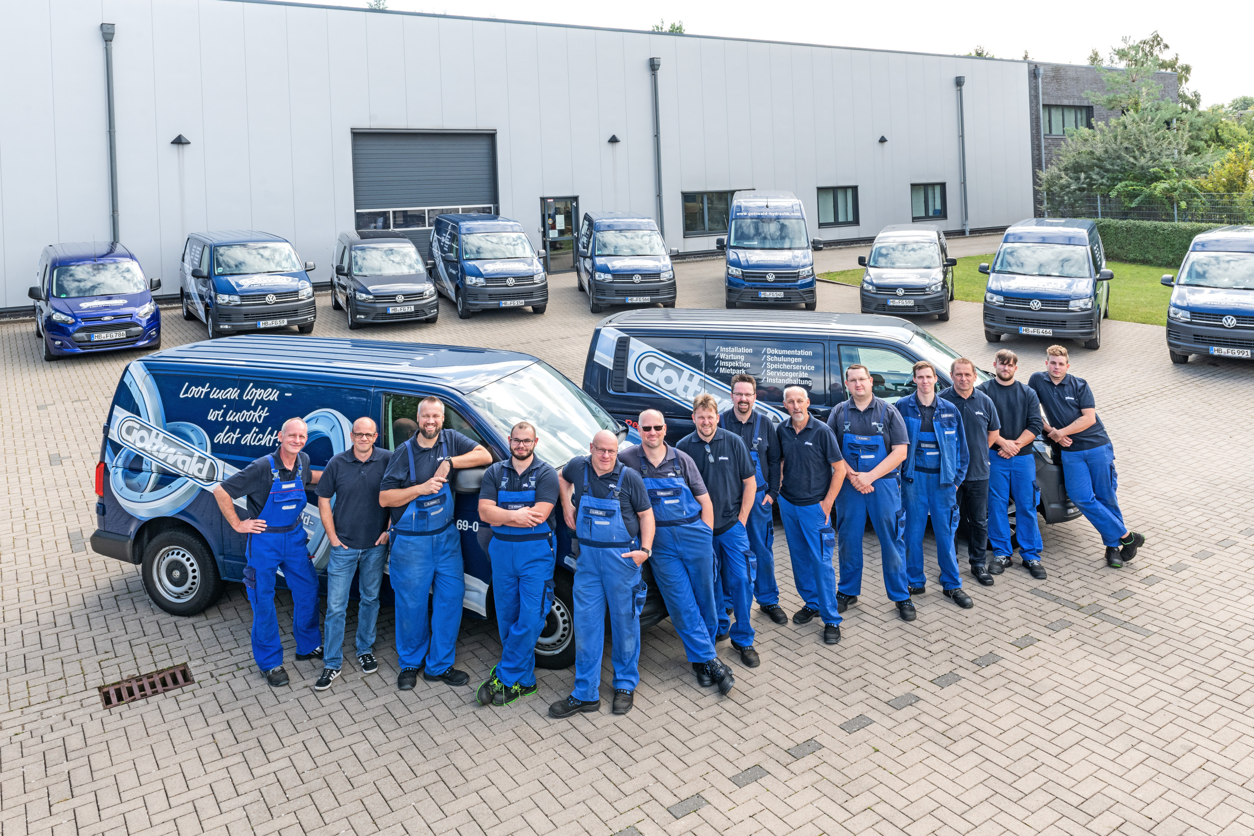 Das Serviceteam von Franz Gottwald steht in Arbeitskleidung vor zwei beschrifteten Firmenfahrzeugen auf dem Betriebshof.