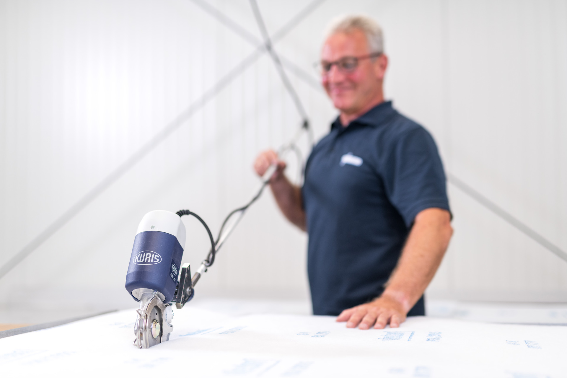 Ein Mitarbeiter von Franz Gottwald schneidet Filtermaterial mit einer Schneidemaschine.