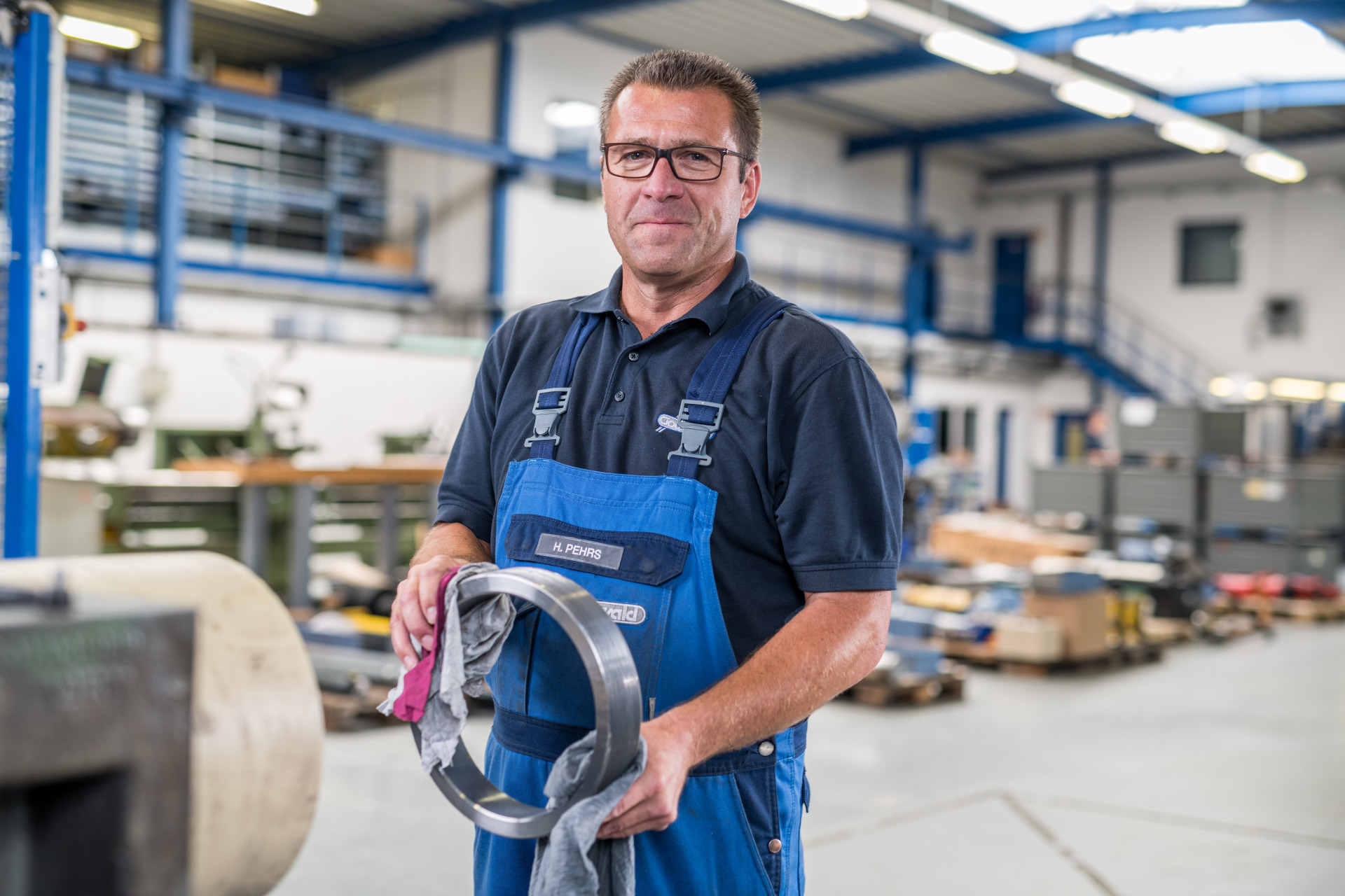 Ein Mitarbeiter von Franz Gottwald reinigt ein metallisches Maschinenteil sorgfältig mit einem Tuch.