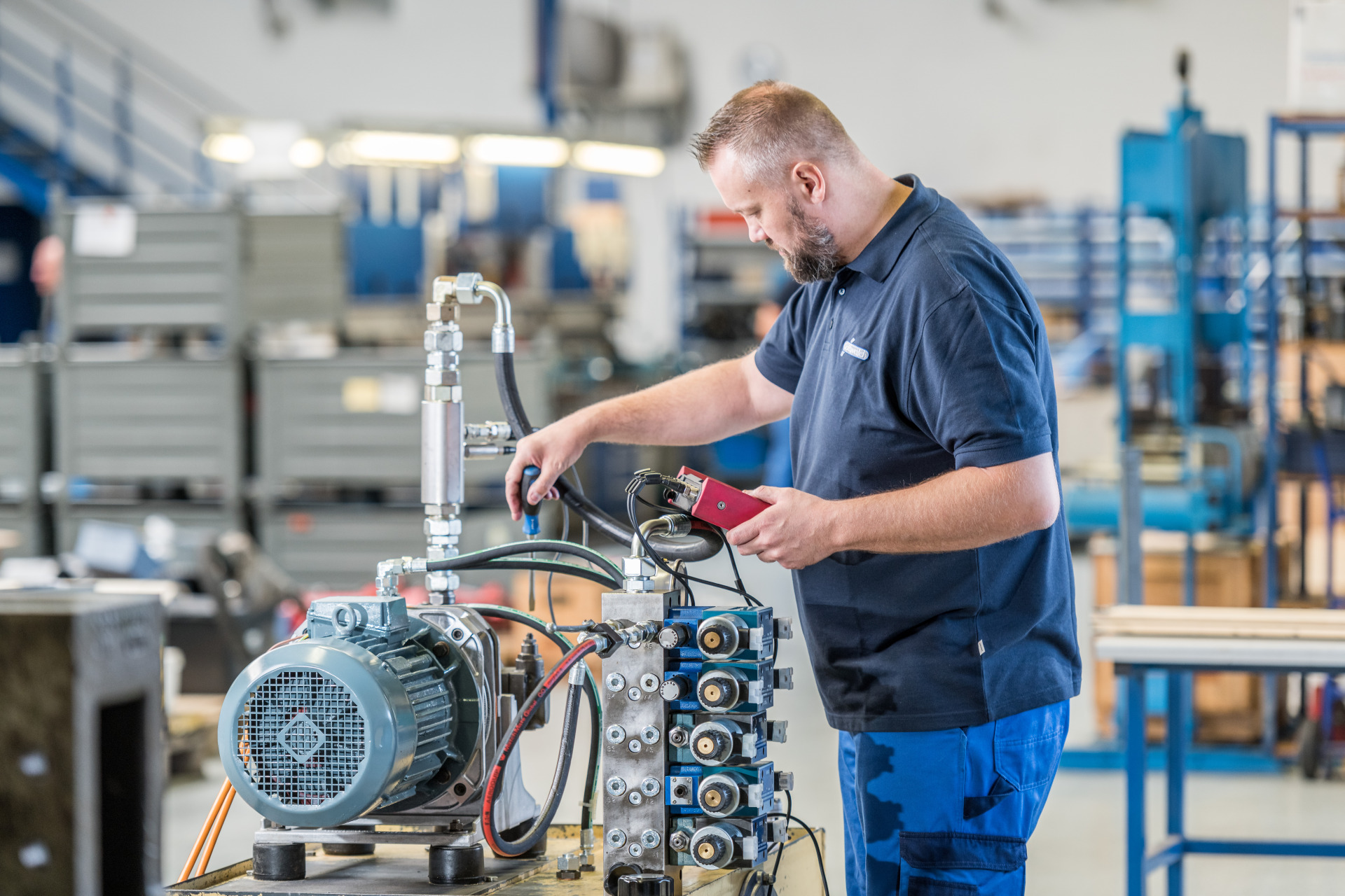 Ein Hydrauliker von Franz Gottwald prüft ein Hydraulikaggregat mit einem elektronischen Messgerät.