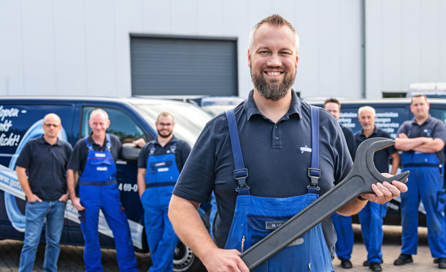 Ein Servicetechniker von Franz Gottwald steht mit einem großen Maulschlüssel vor seinem Team.