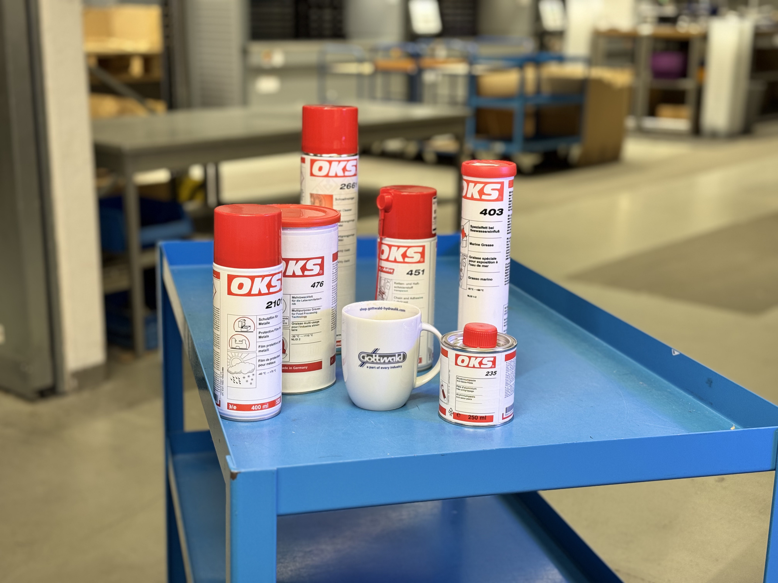 OKS-Schmierstoffe und eine Tasse mit Franz Gottwald Logo auf einem blauen Werkstattwagen