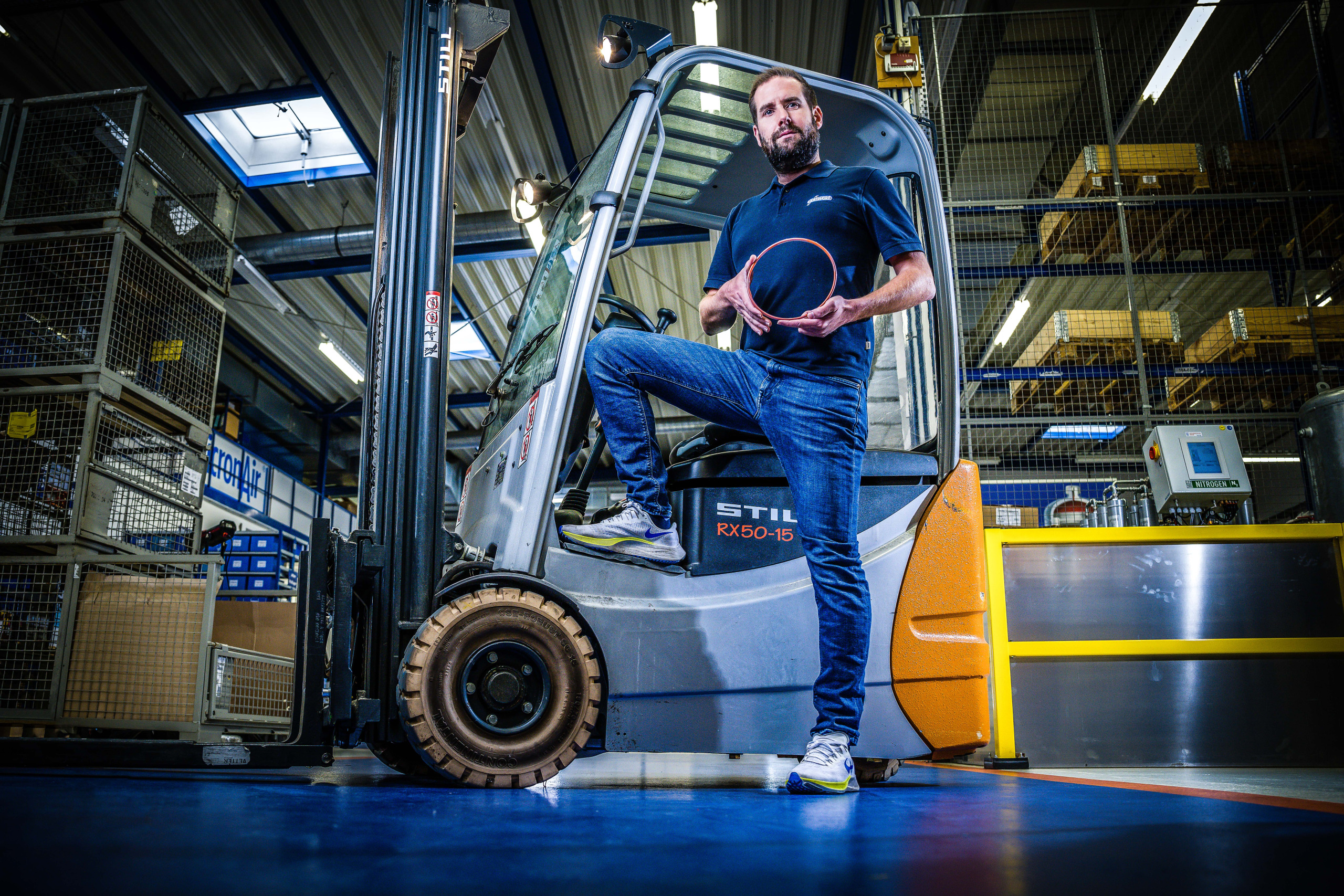 Ein Mitarbeiter der Franz Gottwald GmbH + Co. KG steht mit einem O-Ring vor einem Gabelstapler in der Werkhalle. Dichtungen von Dichta.