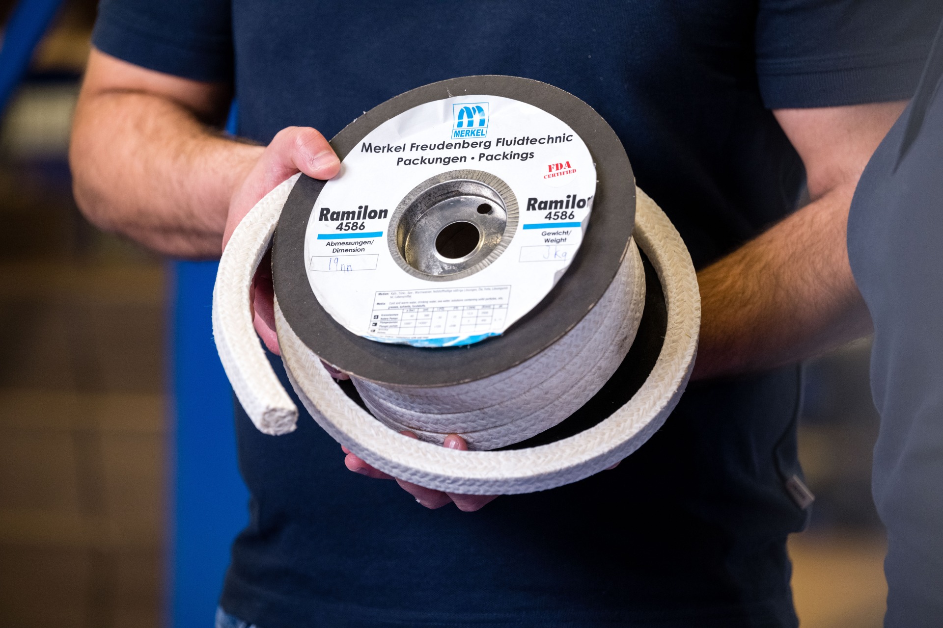 Nahaufnahme einer Packungsrolle vom Typ Ramilon 4586 von Merkel Freudenberg Fluidtechnic in den Händen eines Mitarbeiters.