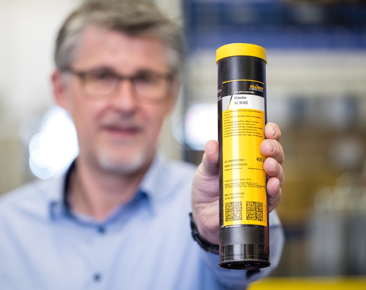 Ein Außendienst Mitarbeiter von Gottwald hält eine Kartusche Schmiermittel in der Hand.