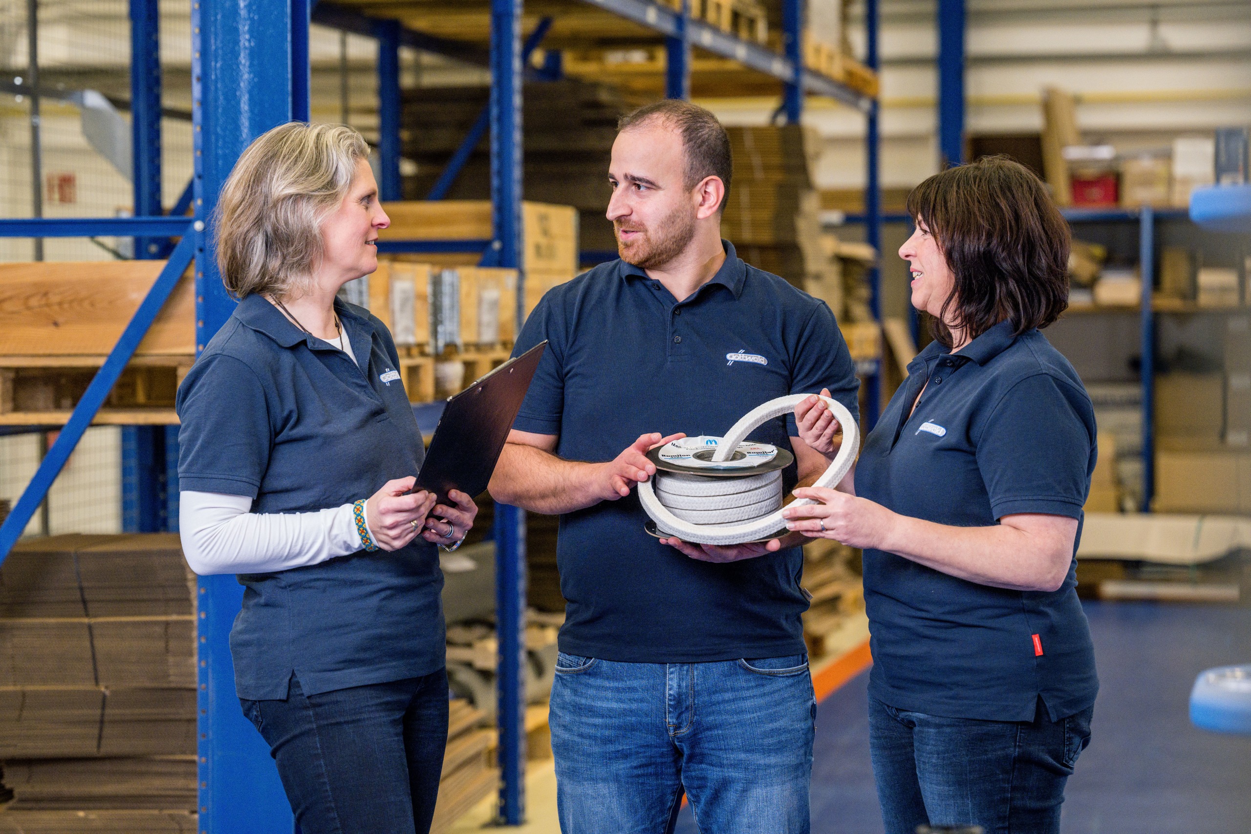 Drei Mitarbeitende der Franz Gottwald GmbH + Co. KG besprechen technische Details zu einer Stopfbuchspackung von Burgmann Packings im Lager.