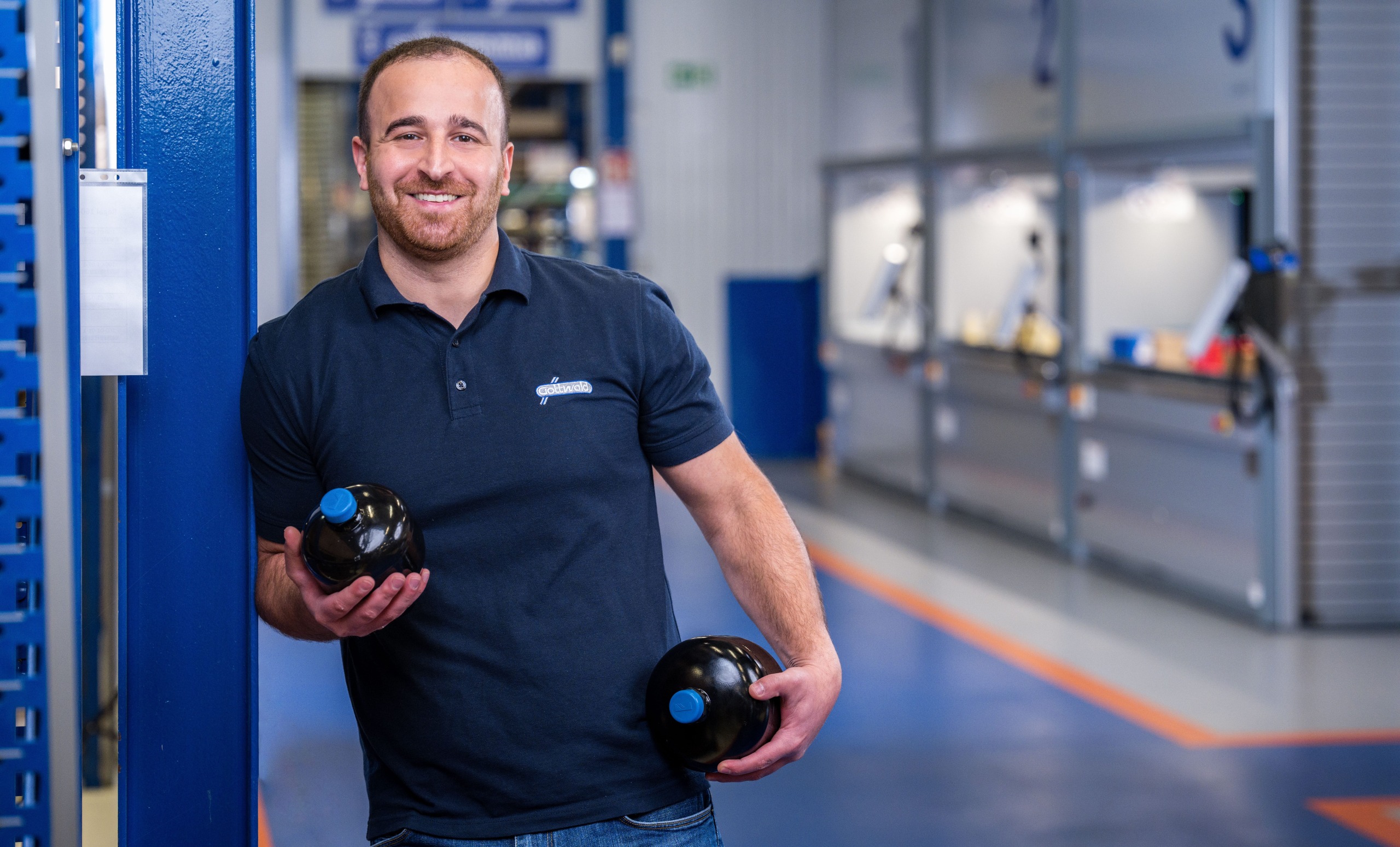 Mitarbeiter der Franz Gottwald GmbH + Co. KG hält zwei schwarze Hydrospeicher von Integral Accumulator in den Händen.