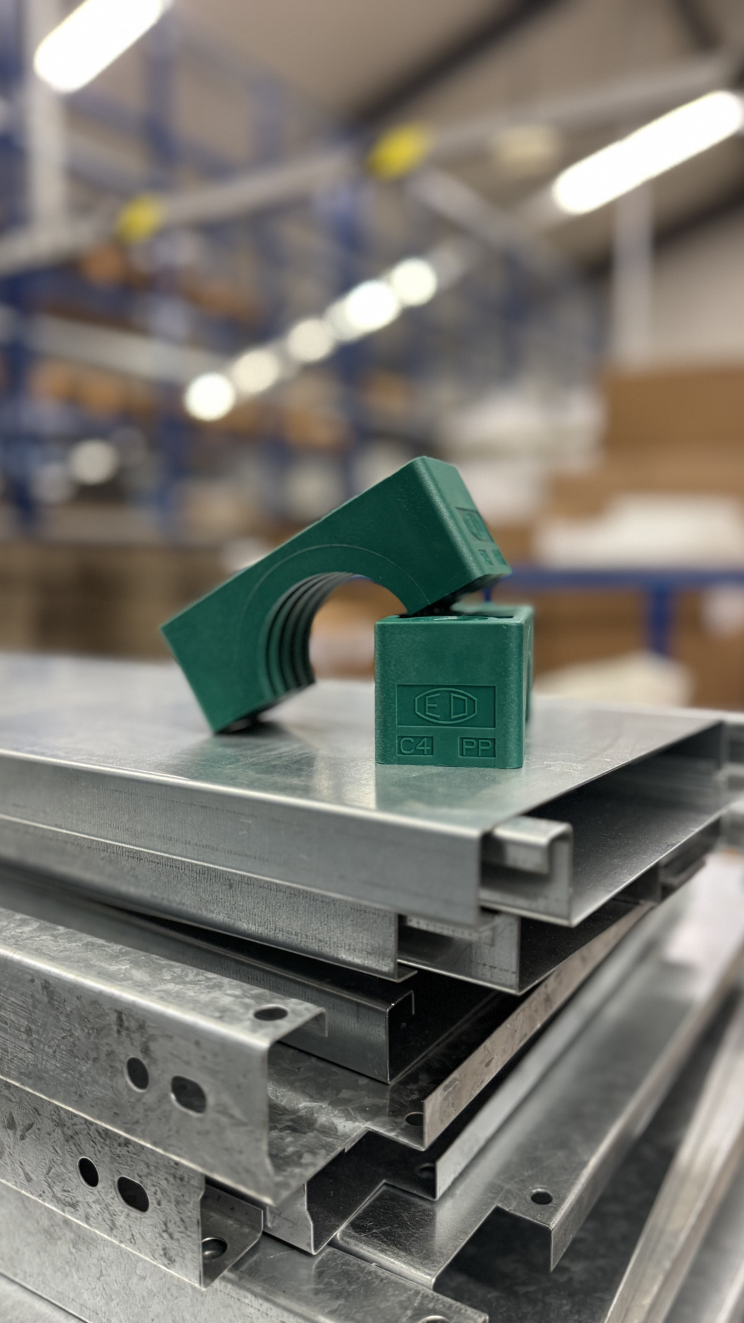 Grüne Parker-Schellenhälften aus Kunststoff liegen auf Metallprofilen im Lager der Franz Gottwald GmbH + Co. KG.