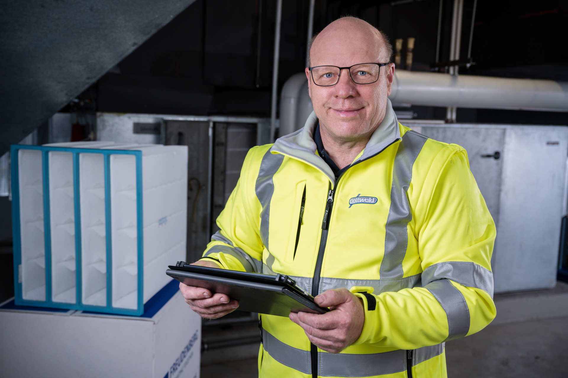 Mitarbeiter von Franz Gottwald prüft mit einem Tablet Luftfilteranlagen vor Ort.