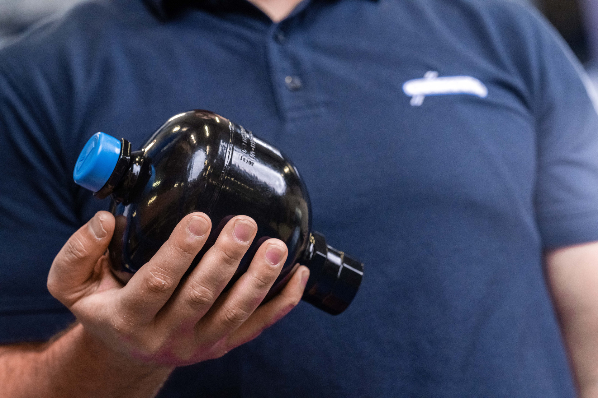 Ein Mitarbeiter der Franz Gottwald GmbH + Co. KG hält einen schwarzen Hydrospeicher in der Hand.