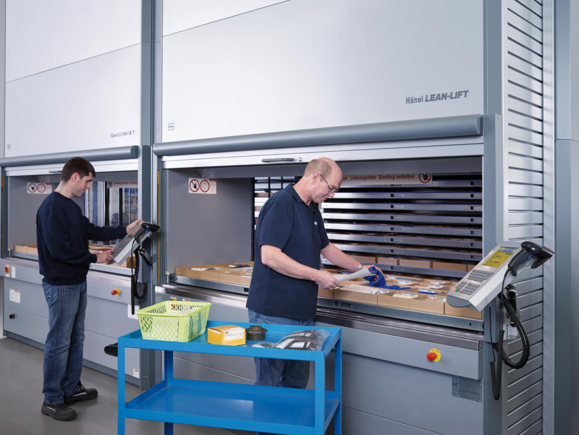 Zwei Mitarbeiter von Franz Gottwald arbeiten an vertikalen Lagerliften vom Typ Hänel Lean-Lift.