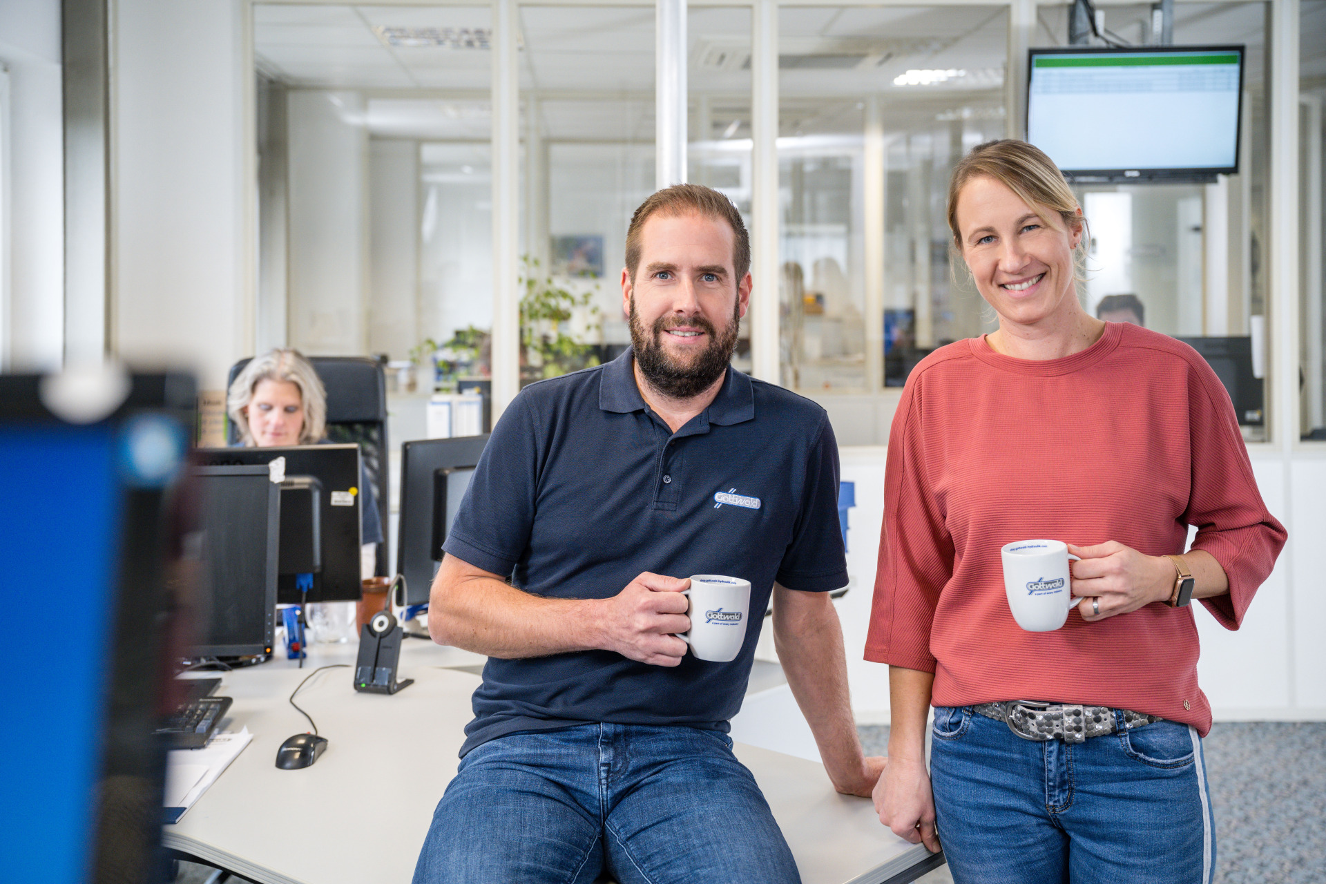 Zwei Mitarbeitende von Gottwald mit Kaffeetassen im Büro.