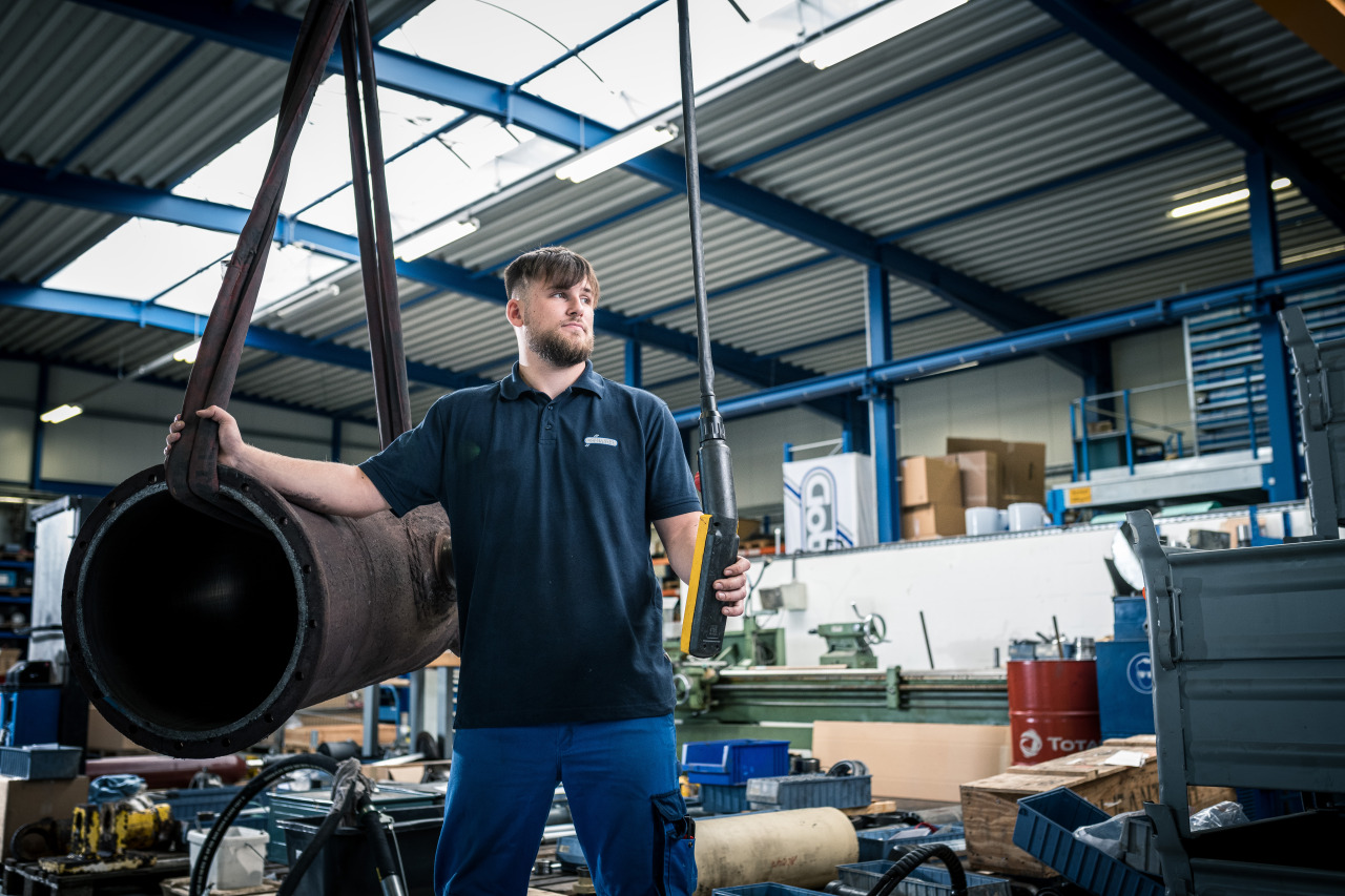 Mitarbeiter von Franz Gottwald steuert ein Hebezeug mit einem großen Hydraulikzylinder in der Werkstatt.