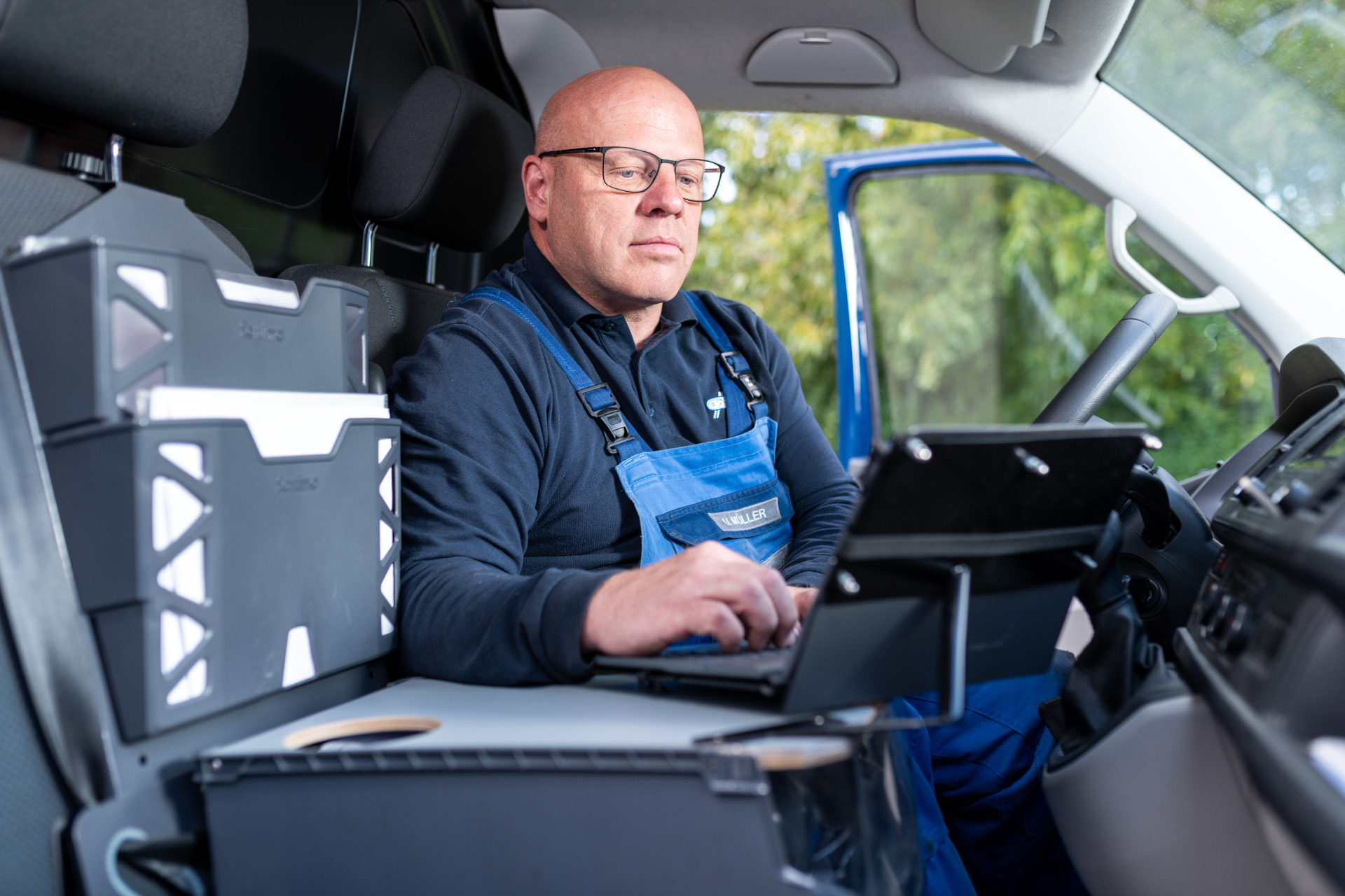 Ein Mitarbeiter für Fluid-Service von Franz Gottwald arbeitet im Fahrzeug mit einem Laptop und organisiert Unterlagen.