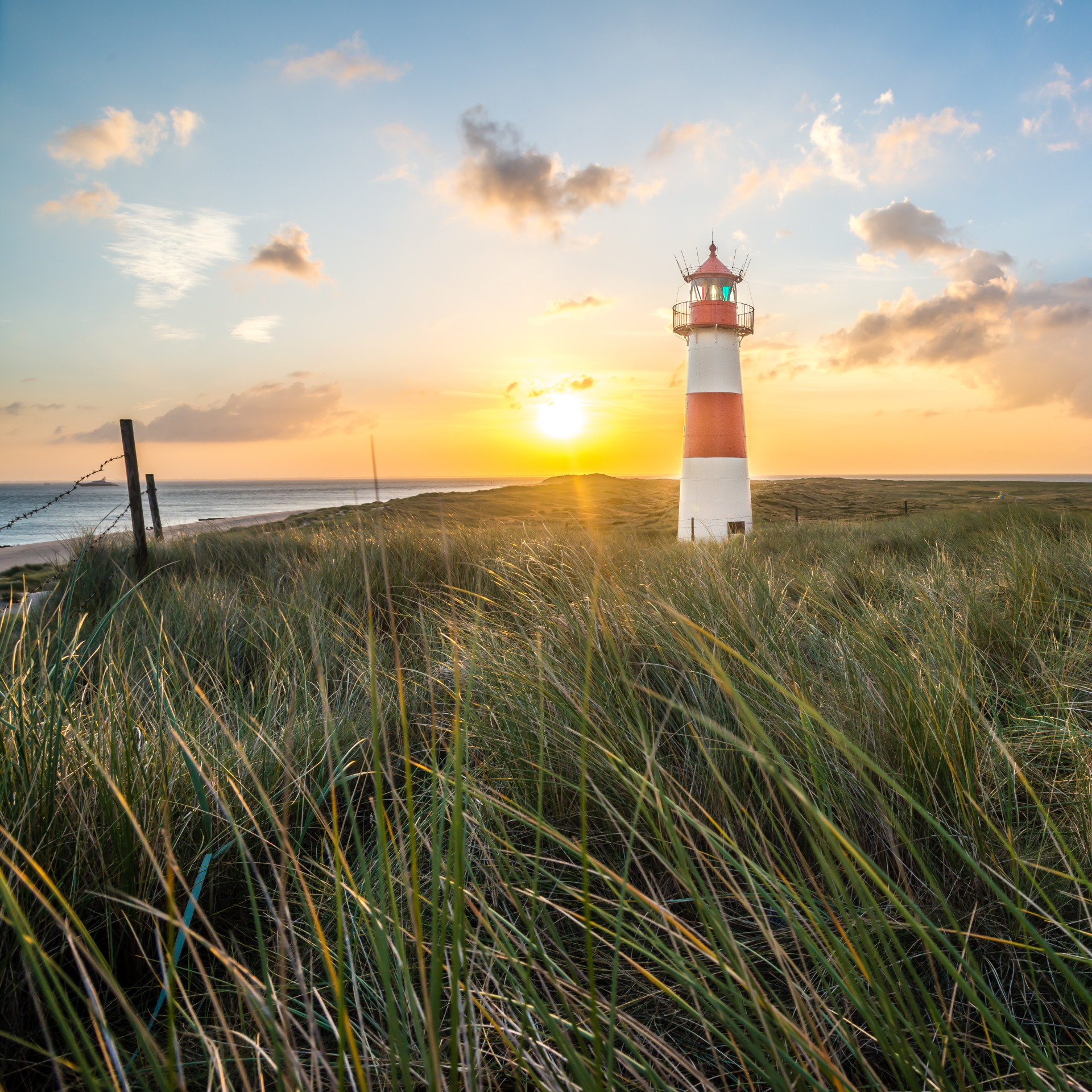 Leuchtturm in den Dünen an der Nordsee bei Sonnenuntergang. Spiegelt Nachhaltigkeit wider.