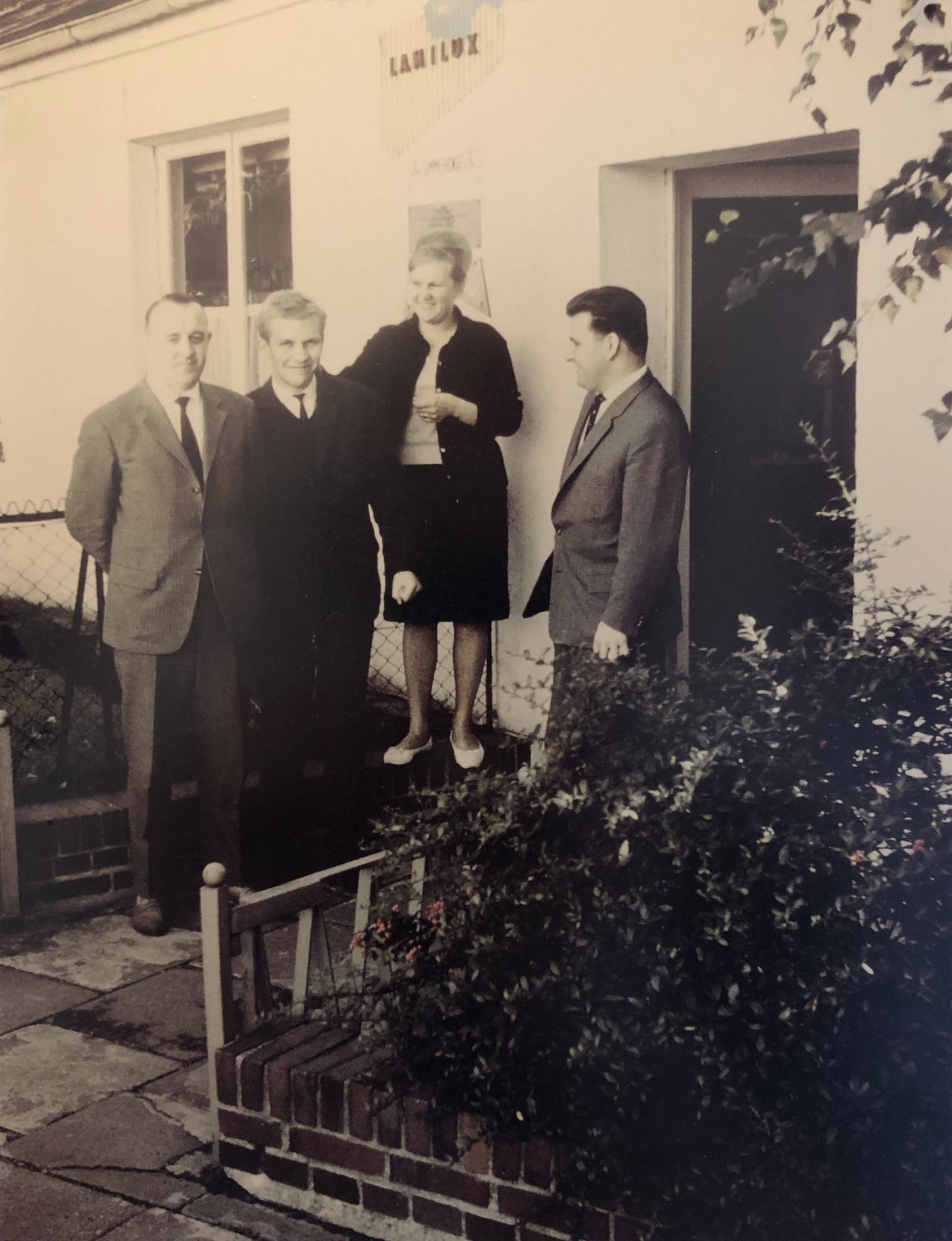 Historic photo of four people standing in front of a building entrance, likely from the early years of Franz Gottwald.