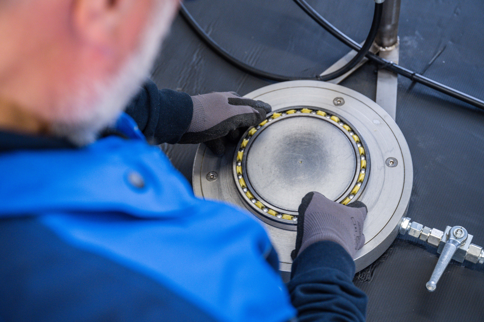 Ein Mitarbeiter von Franz Gottwald trägt in der Fertigung Schmierstoff auf ein offenes Wälzlager auf.