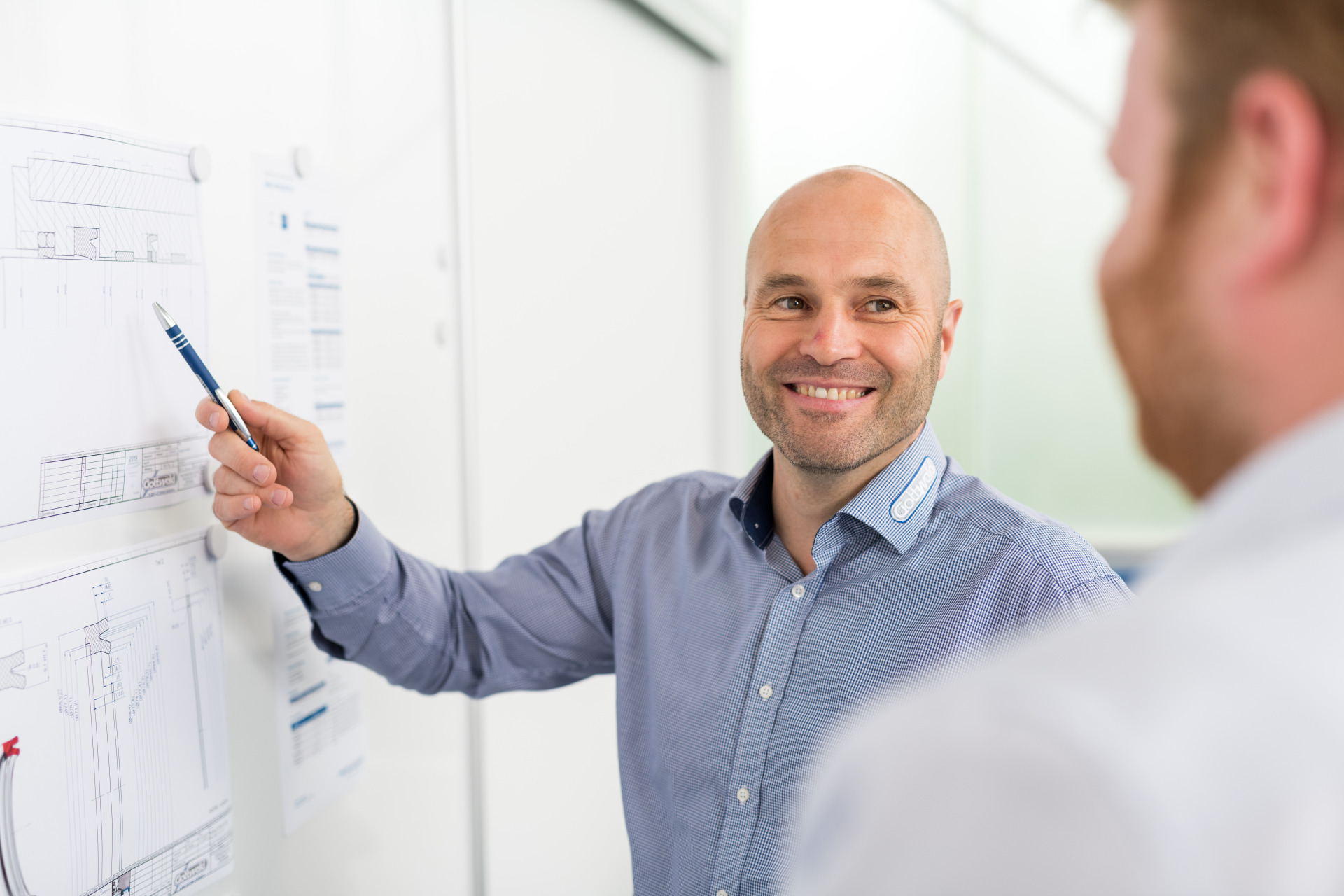 Mitarbeiter von Franz Gottwald zeigt technische Zeichnung und erklärt Details.