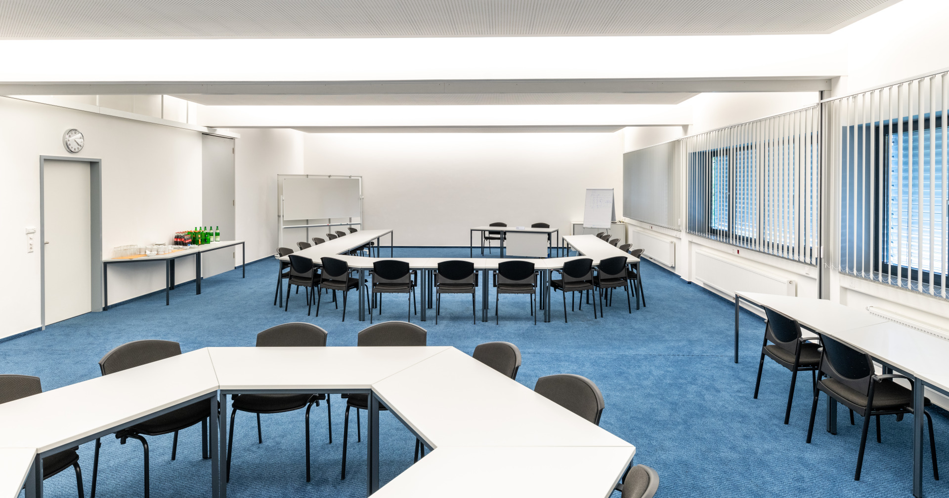 Schulungsraum der Fluid-Akademie von Franz Gottwald mit U-förmig aufgestellten Tischen und Getränken auf einem Seitentisch.
