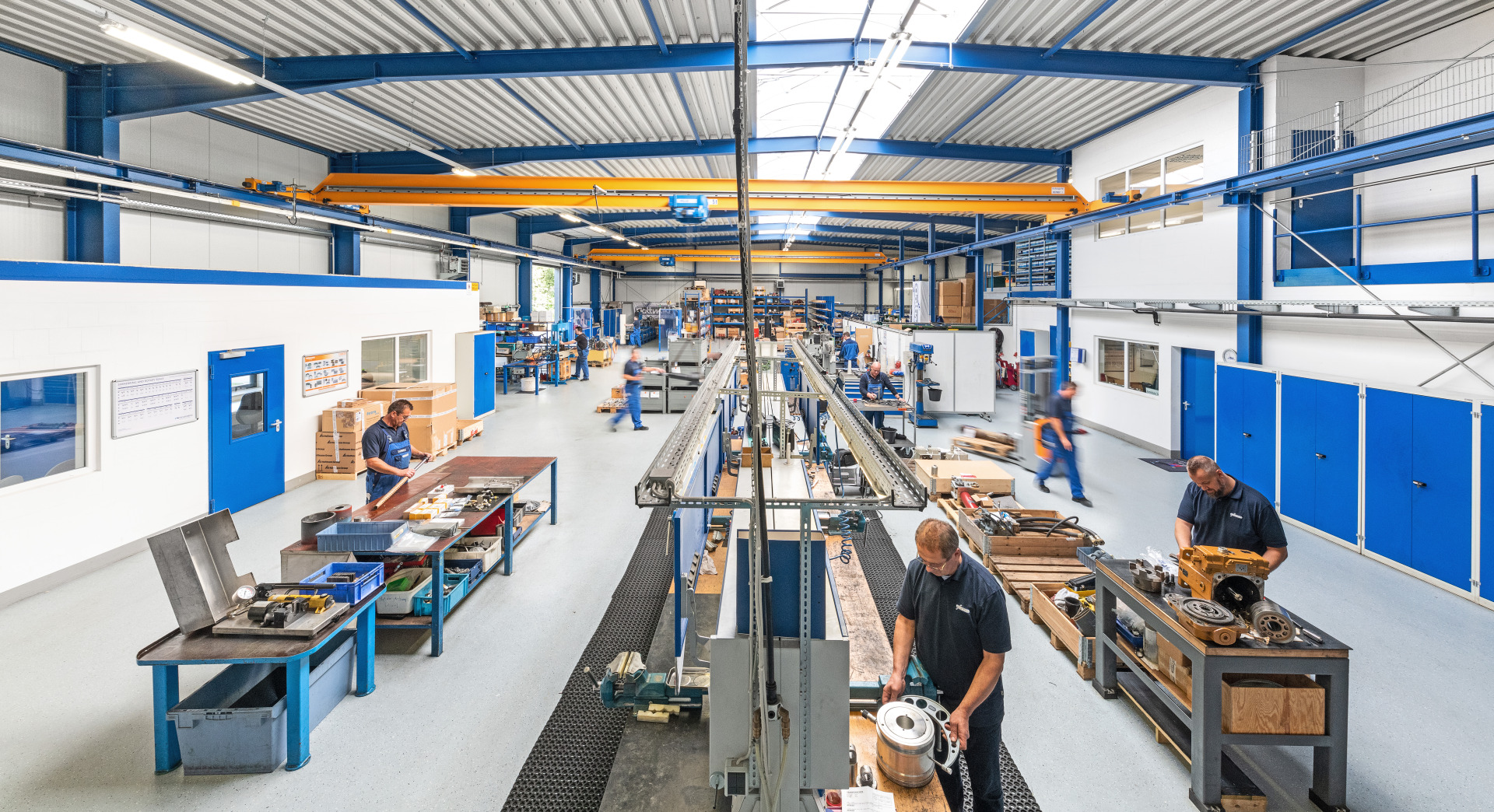 Blick in die großzügige Hydraulik-Werkstatt von Franz Gottwald mit mehreren Arbeitsstationen und Mitarbeitern bei der Montage.