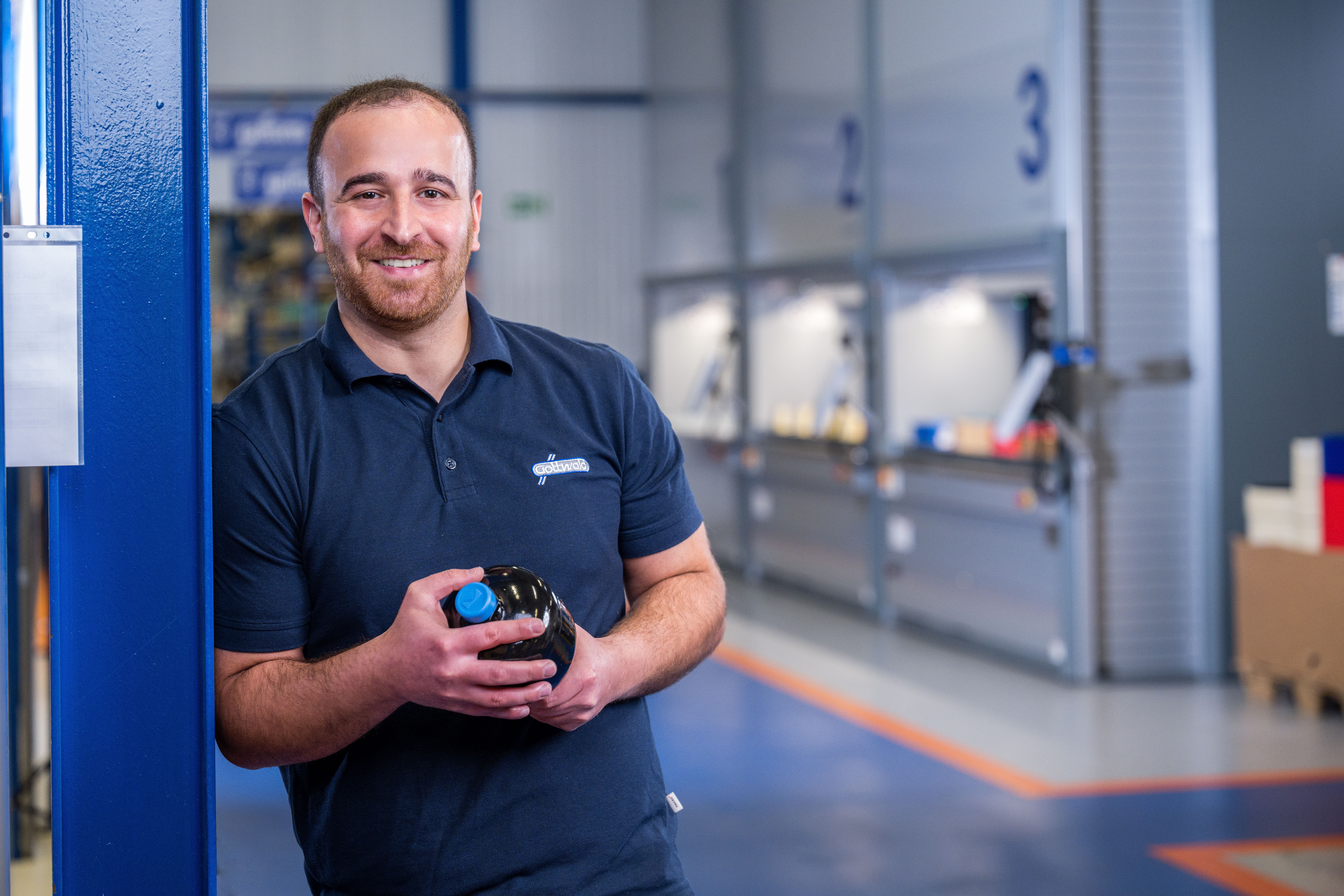 Mitarbeiter von Franz Gottwald hält einen Hydraulikspeicher in der Werkstatt in den Händen. Druckspeichertechnik.